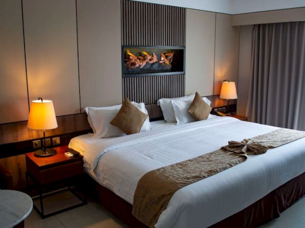A cozy hotel room with a neatly made bed, two bedside tables each with a lamp, and a decorative piece hanging above the bed.