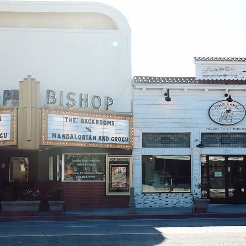 A storefront plaza with a &ldquo;Starship Hop&rdquo; sign, &ldquo;The Backrooms&rdquo; and &ldquo;Mandalorian and Grogu,&rdquo; plus &ldquo;Yogurt | Pie | Wine&rdquo; signage.